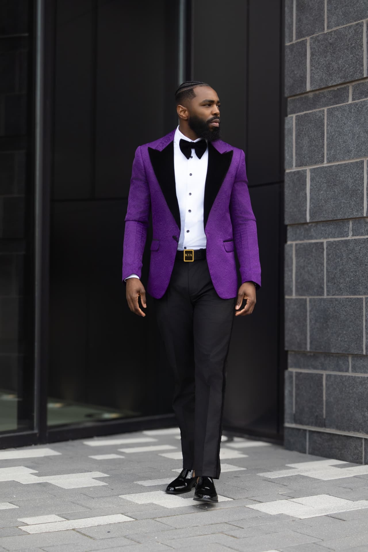 Myron Ross, founder of Krowned Talent Agency, in a purple tuxedo jacket with a gold KTA belt buckle